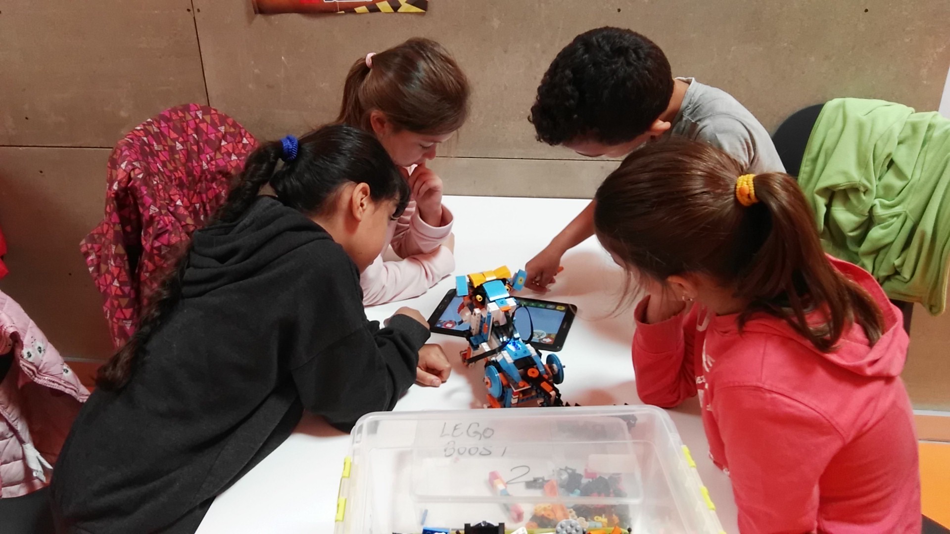 Niños y niñas trabajando con una tablet y un robot