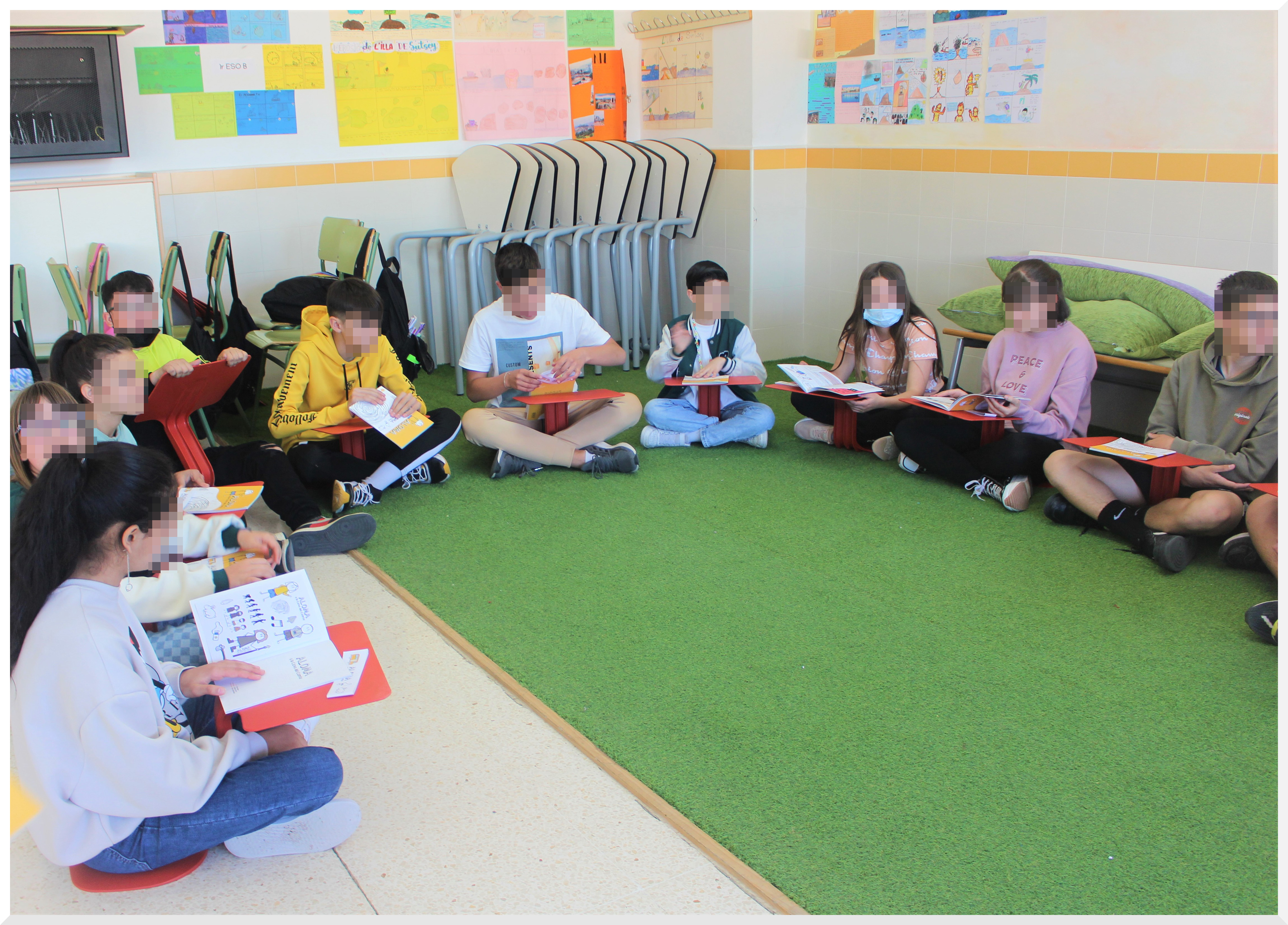 Alumnado sentado en círculo en el césped AdF para leer