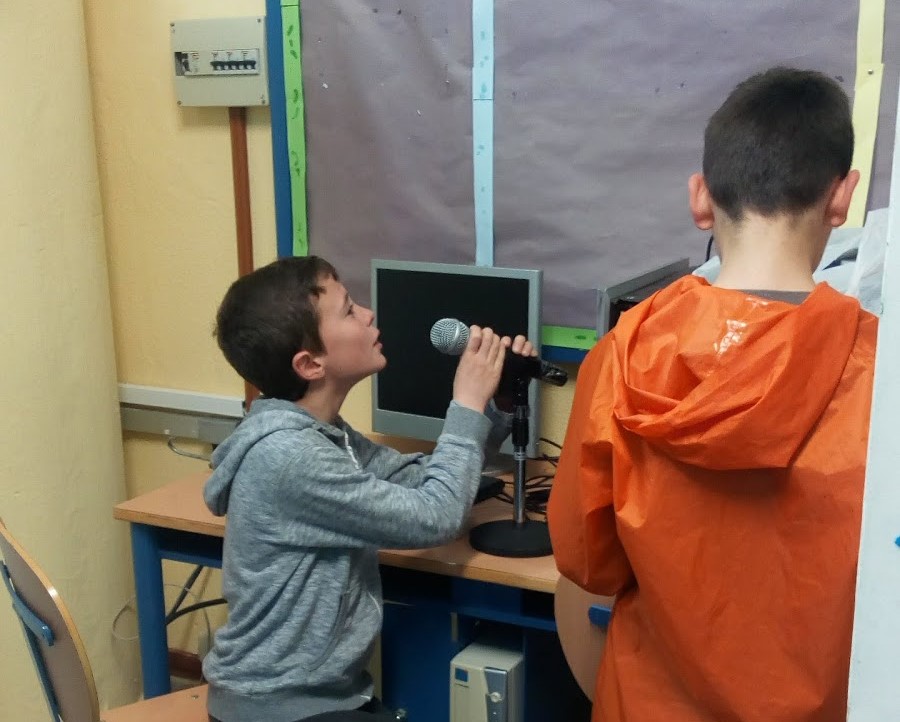 Dos estudiantes frente a un micrófono en la zona de audio
