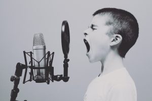 Niño gritando en micrófono de estudio de grabación