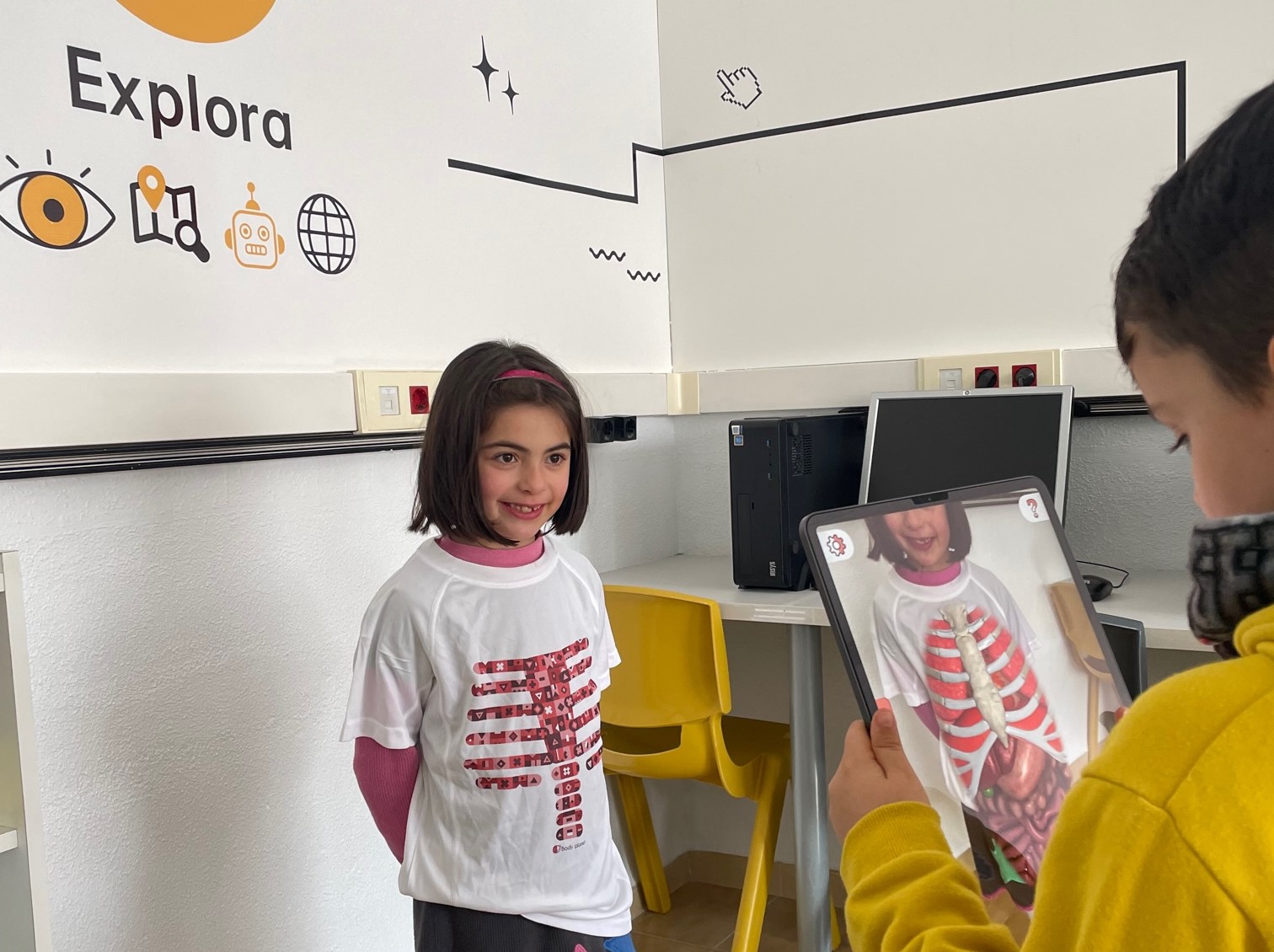 Alumno utilizando realidad aumentada sobre la camiseta de una alumna para explorar el interior del cuerpo humano