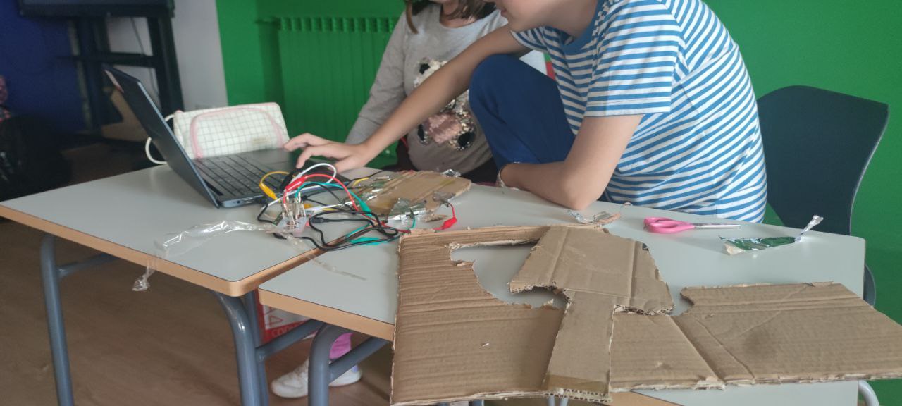 Alumna y alumno creando material para programar con placas makey-makey