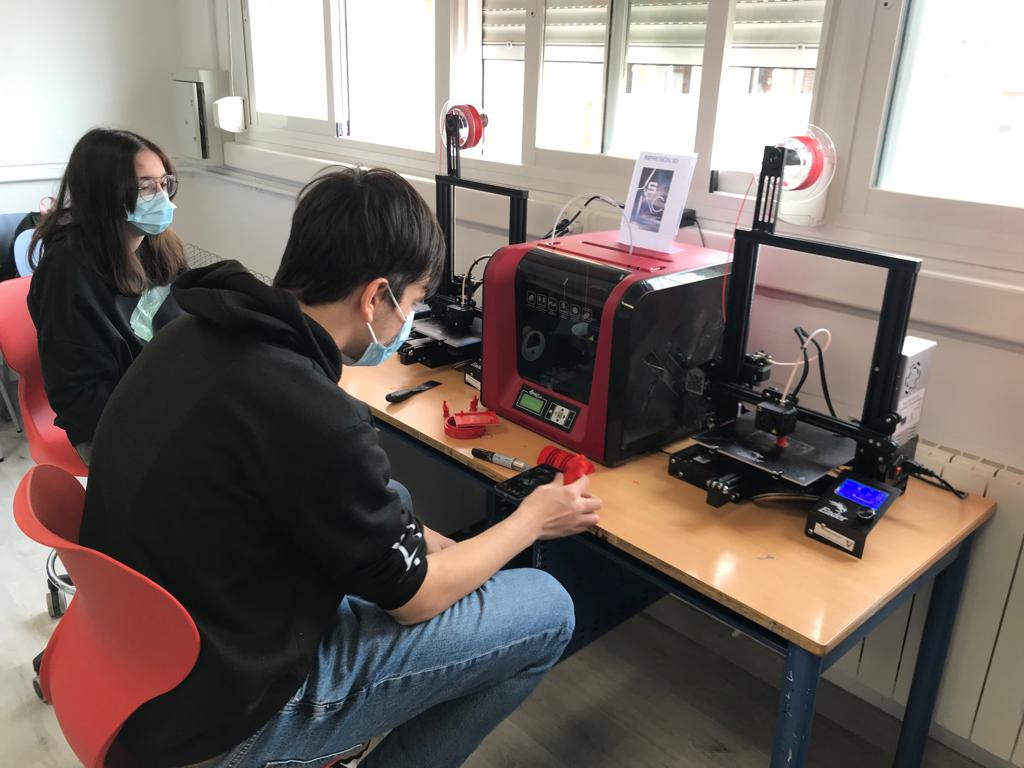 Alumno y alumna utilizando la impresora 3D
