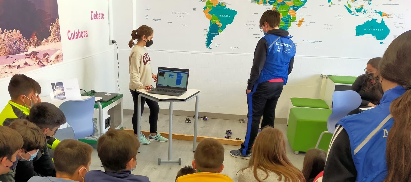 Alumno y alumna mostrando la programación de robots maqueen y su resultado ante el grupo-clase