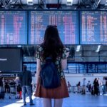 Mujer en aeropuerto frente panel vuelos