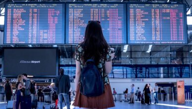 Mujer en aeropuerto frente panel vuelos